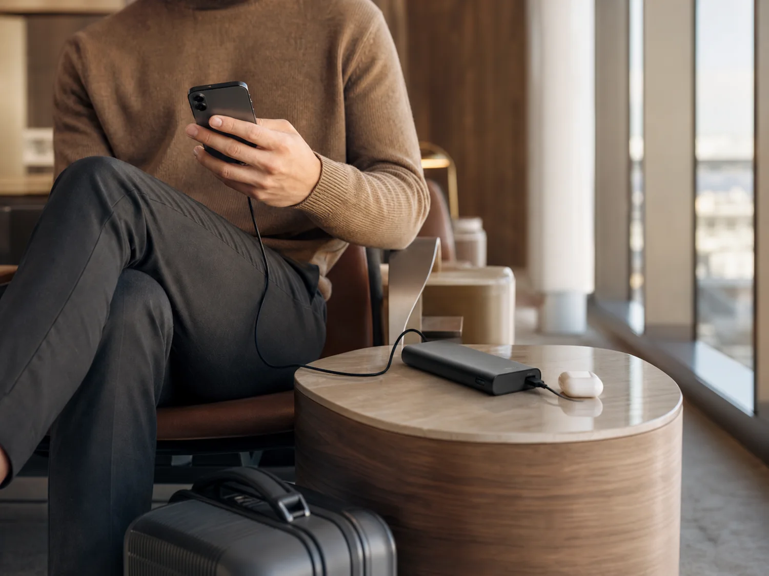 A traveler charging a phone with a compact power bank